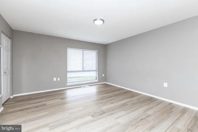 a view of an empty room with wooden floor and windows