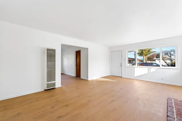 a view of an empty room with a fireplace and window