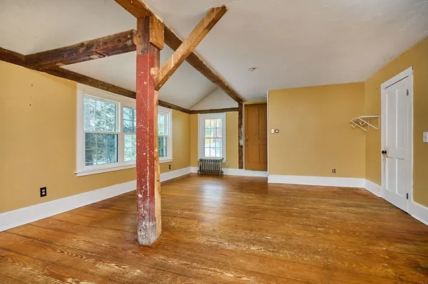 a view of an empty room with window and wooden floor