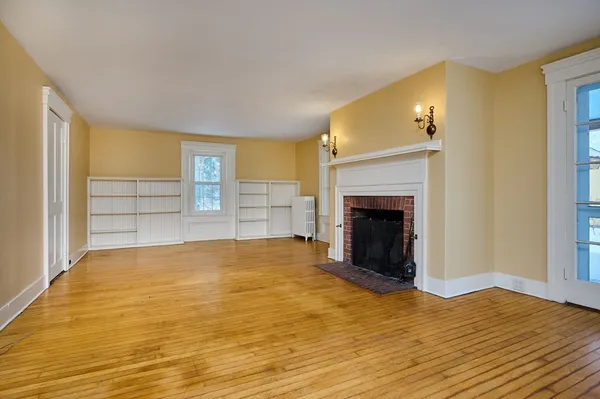 a view of empty room with wooden floor and fireplace