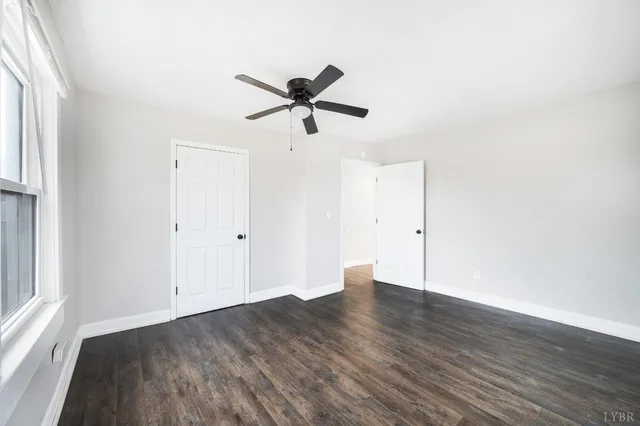 a view of a hallway with wooden floor and a bathroom