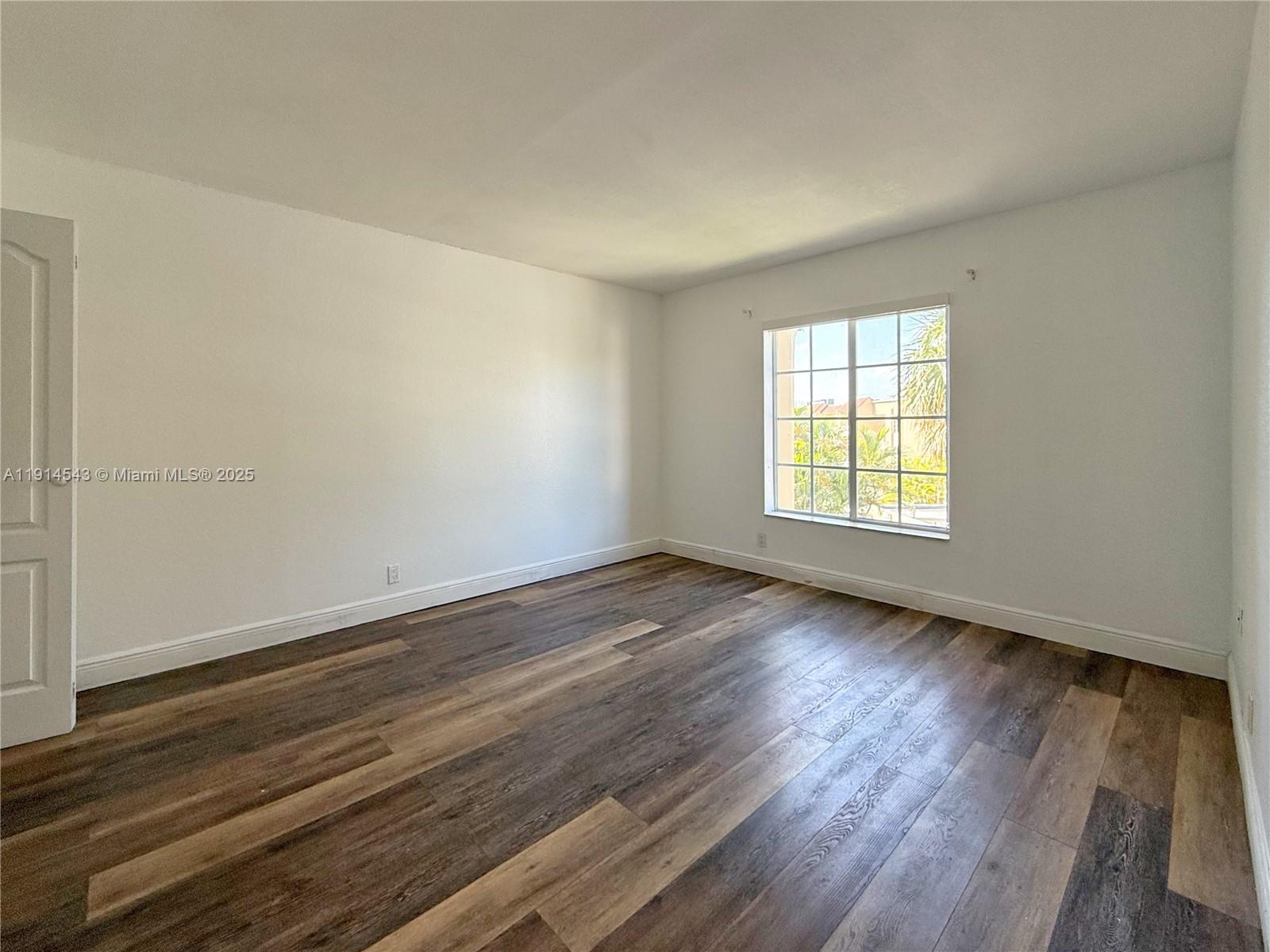 5231 Geneva Court, Unit 307 Doral, FL 33166 - Photo 16 of 26 an empty room with wooden floor and windows