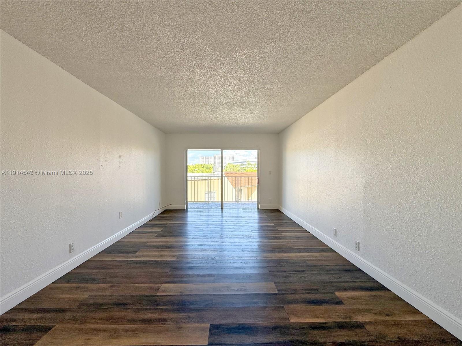 5231 Geneva Court, Unit 307 Doral, FL 33166 - Photo 6 of 26 a view of an empty room with wooden floor and window