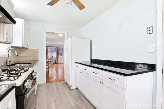 a kitchen with granite countertop white cabinets and appliances