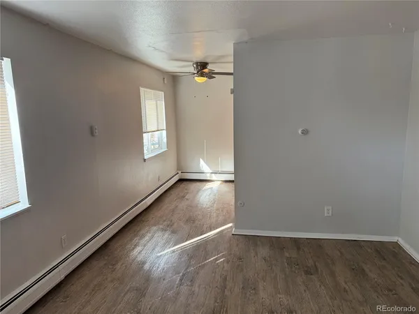 an empty room with wooden floor and windows