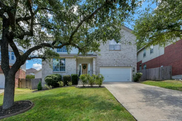 a front view of a house with a garden and trees