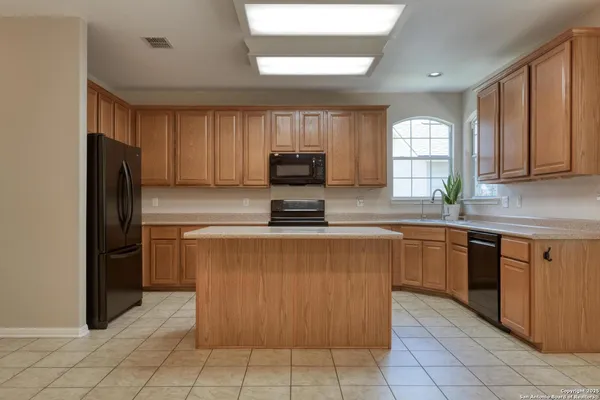 a kitchen with granite countertop a refrigerator and a stove top oven