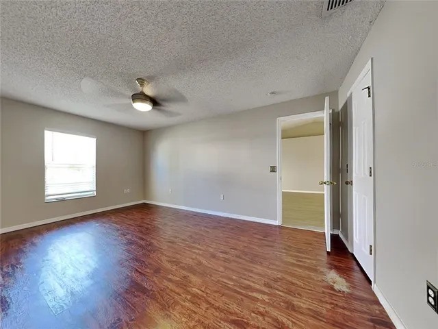 an empty room with wooden floor cabinet and windows