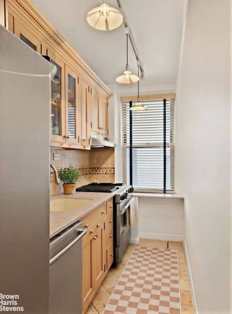 220 East 73rd Street, Unit 9H Manhattan, NY 10021 - Photo 7 of 15 a kitchen with stainless steel appliances granite countertop a stove a sink and a refrigerator