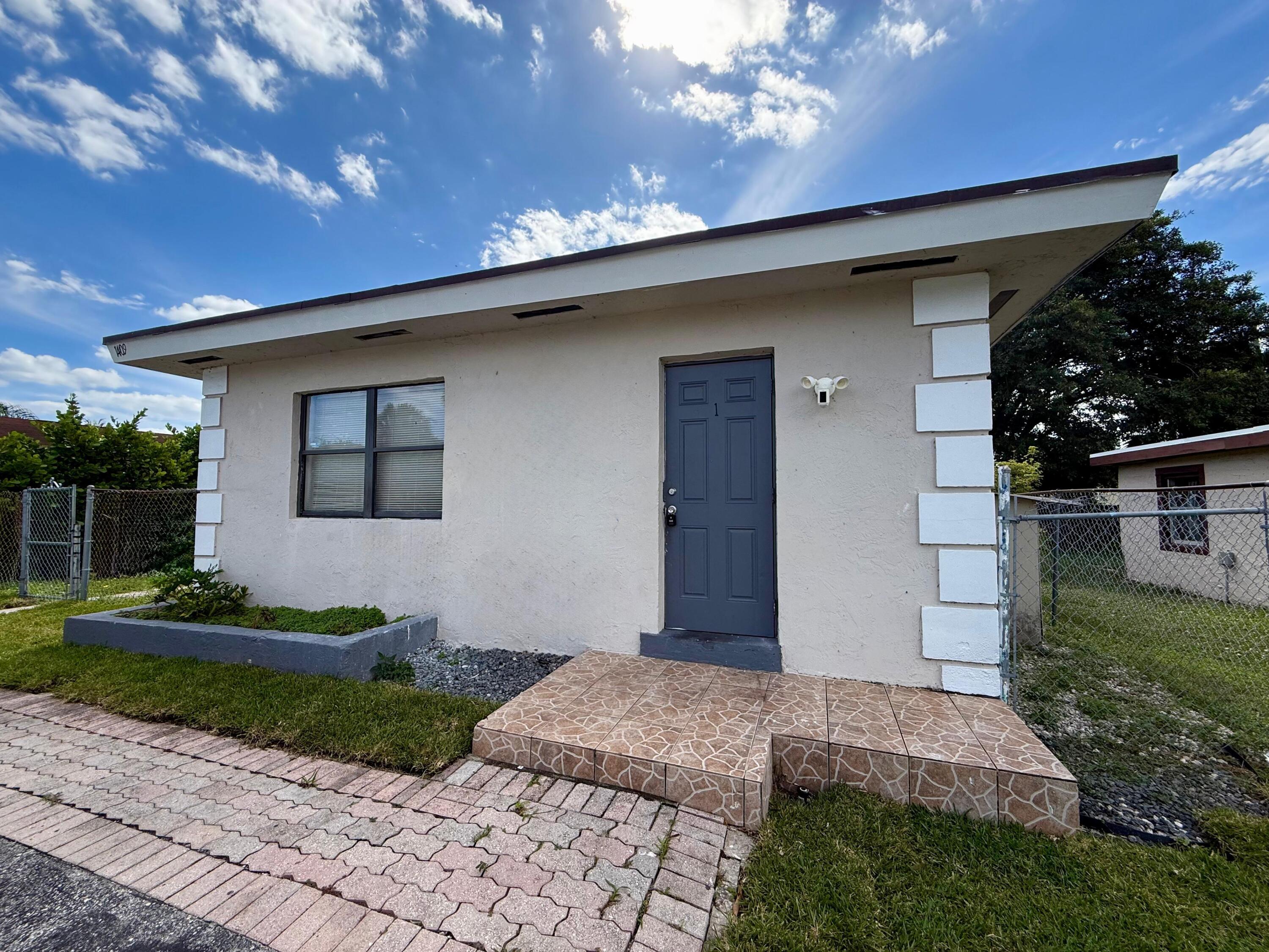 1409 West 33rd Street, Unit 1 Riviera Beach, FL 33404 - Photo 6 of 13 a front view of a house with a yard
