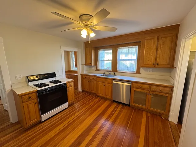 a kitchen with stainless steel appliances granite countertop wooden cabinets a sink a stove a refrigerator with wooden floor