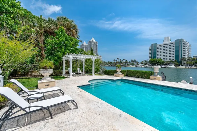 a view of a swimming pool and lounge chairs in back yard of a house