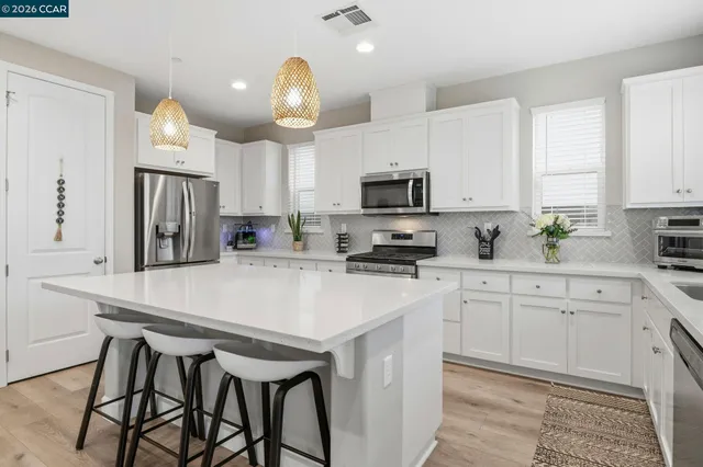 a kitchen with kitchen island granite countertop white cabinets and stainless steel appliances