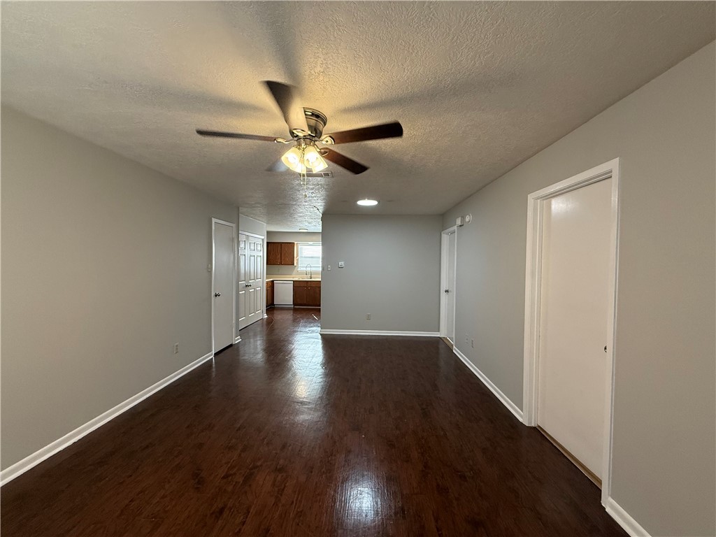 922 Spring Loop, Unit C College Station, TX 77840 - Photo 2 of 11 Unfurnished living room with a textured ceiling, dark wood-type flooring, and a ceiling fan