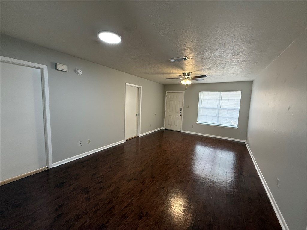 922 Spring Loop, Unit C College Station, TX 77840 - Photo 3 of 11 Spare room with dark wood finished floors and a textured ceiling