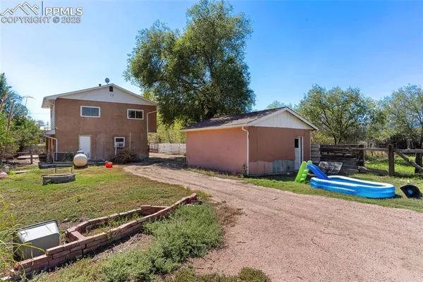 a view of backyard with wooden fence and large trees