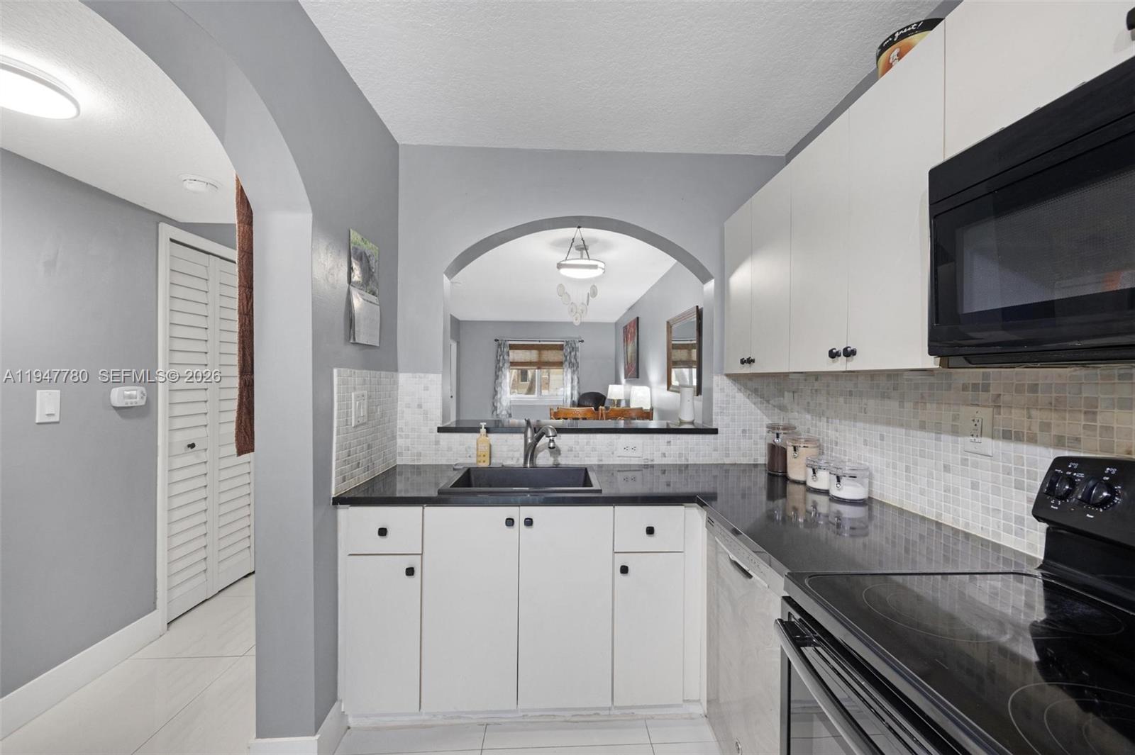 985 Northeast 33rd Terrace, Unit 102 Homestead, FL 33033 - Photo 12 of 20 a kitchen with granite countertop a sink and a stove top oven with wooden floor