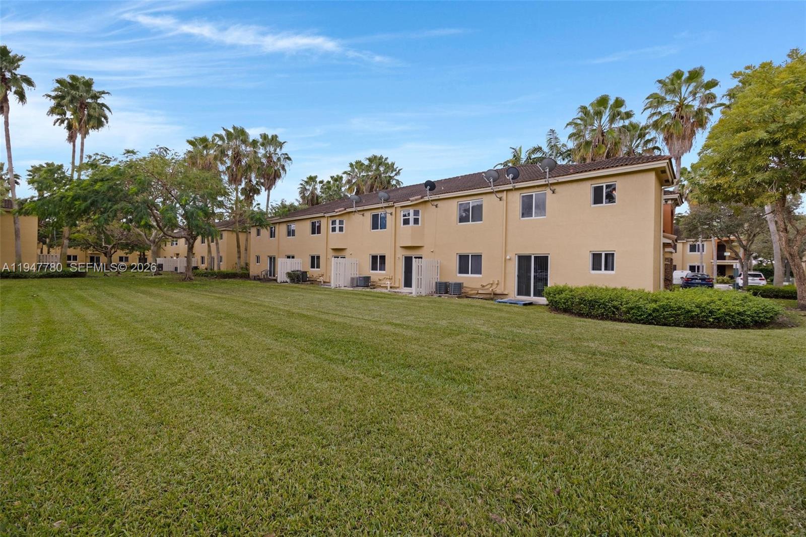 985 Northeast 33rd Terrace, Unit 102 Homestead, FL 33033 - Photo 19 of 20 a view of a white house with a big yard and large trees
