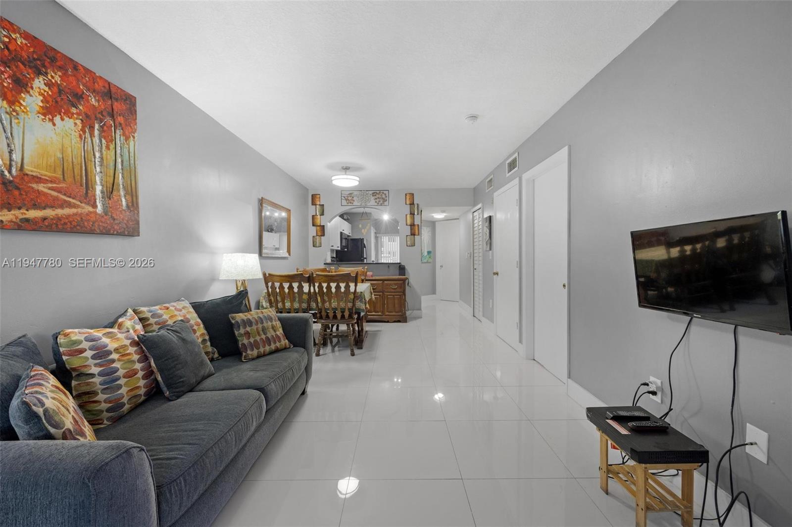 985 Northeast 33rd Terrace, Unit 102 Homestead, FL 33033 - Photo 4 of 20 a living room with furniture and a flat screen tv
