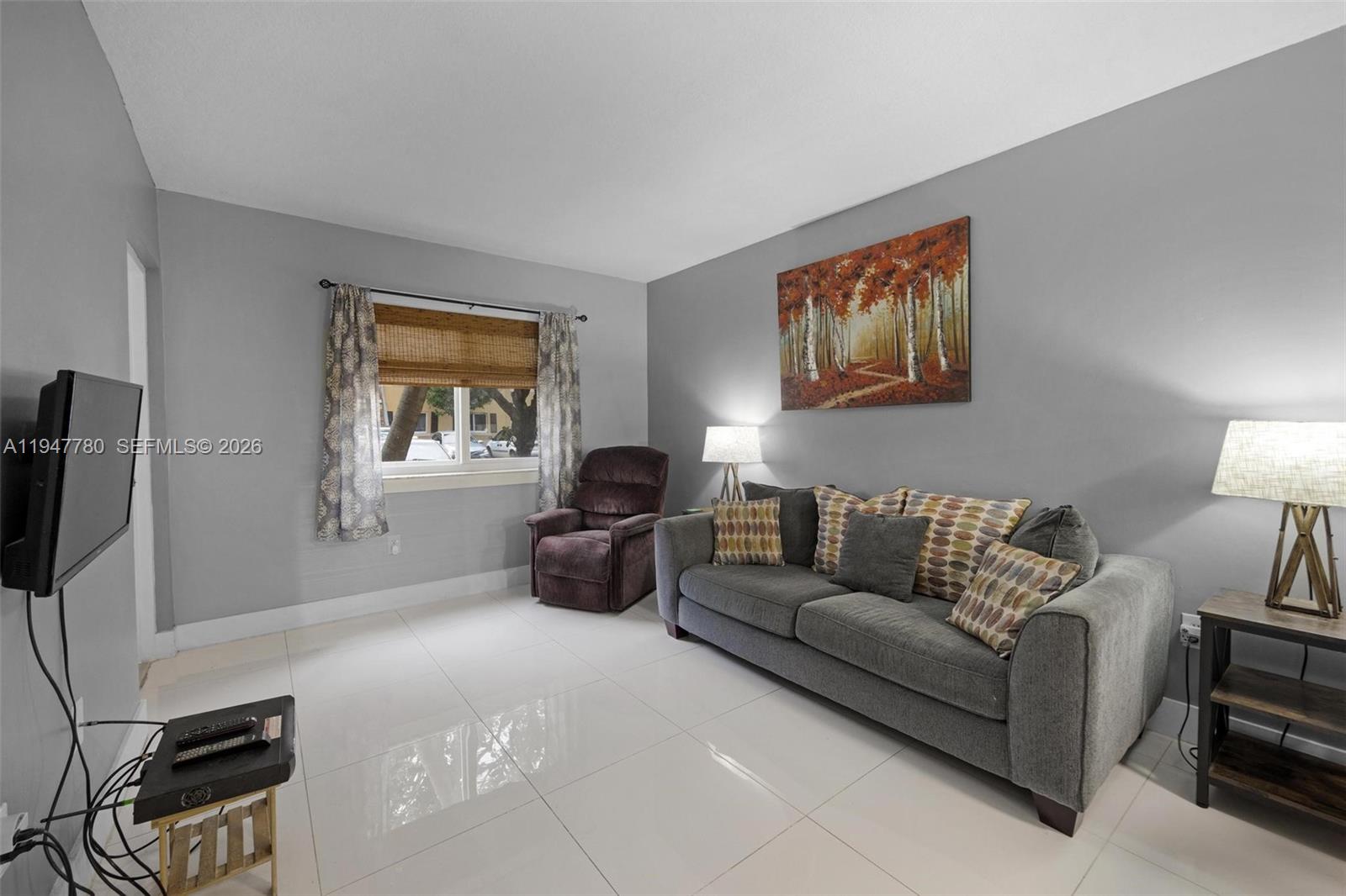 985 Northeast 33rd Terrace, Unit 102 Homestead, FL 33033 - Photo 6 of 20 a living room with furniture and a flat screen tv