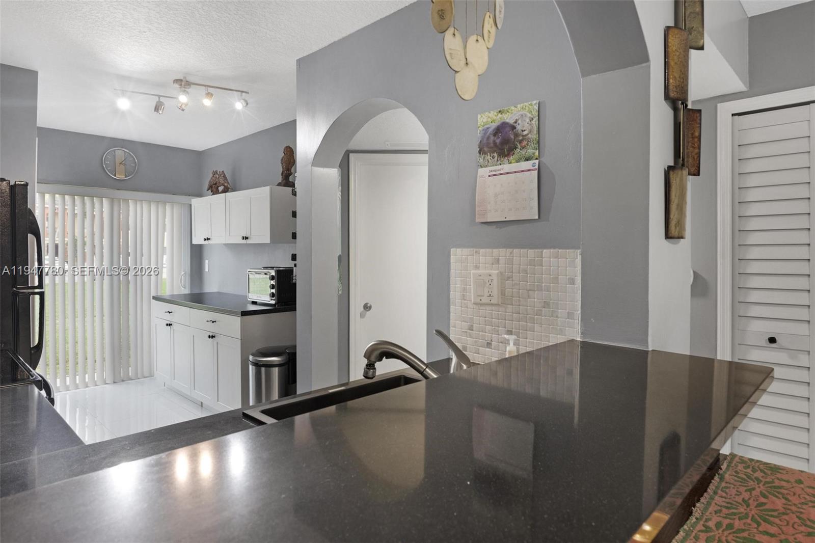 985 Northeast 33rd Terrace, Unit 102 Homestead, FL 33033 - Photo 7 of 20 a kitchen with stainless steel appliances granite countertop a refrigerator a stove a sink and white cabinets with wooden floor