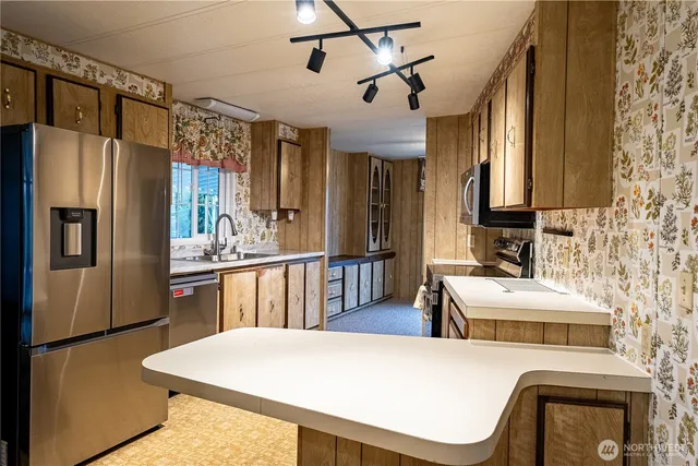 a kitchen with stainless steel appliances a refrigerator a sink a stove and white cabinets