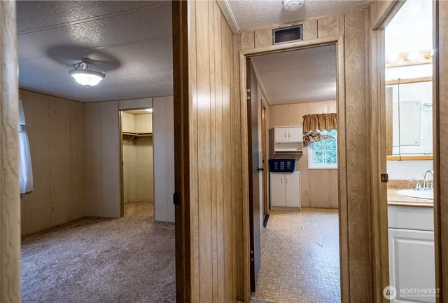 a view of a hallway with wooden floor and a bathroom