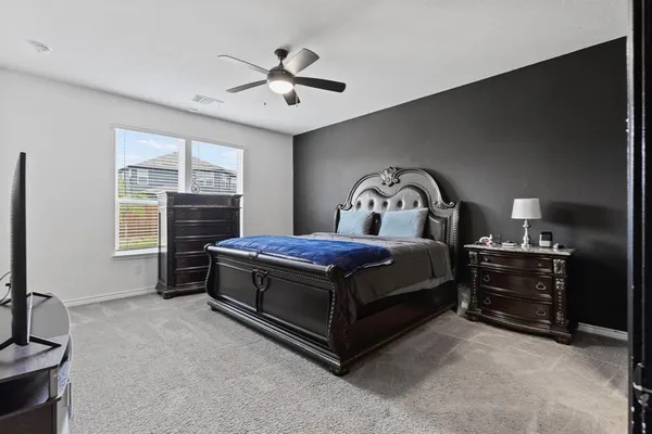 a spacious bedroom with a bed and a flat screen tv