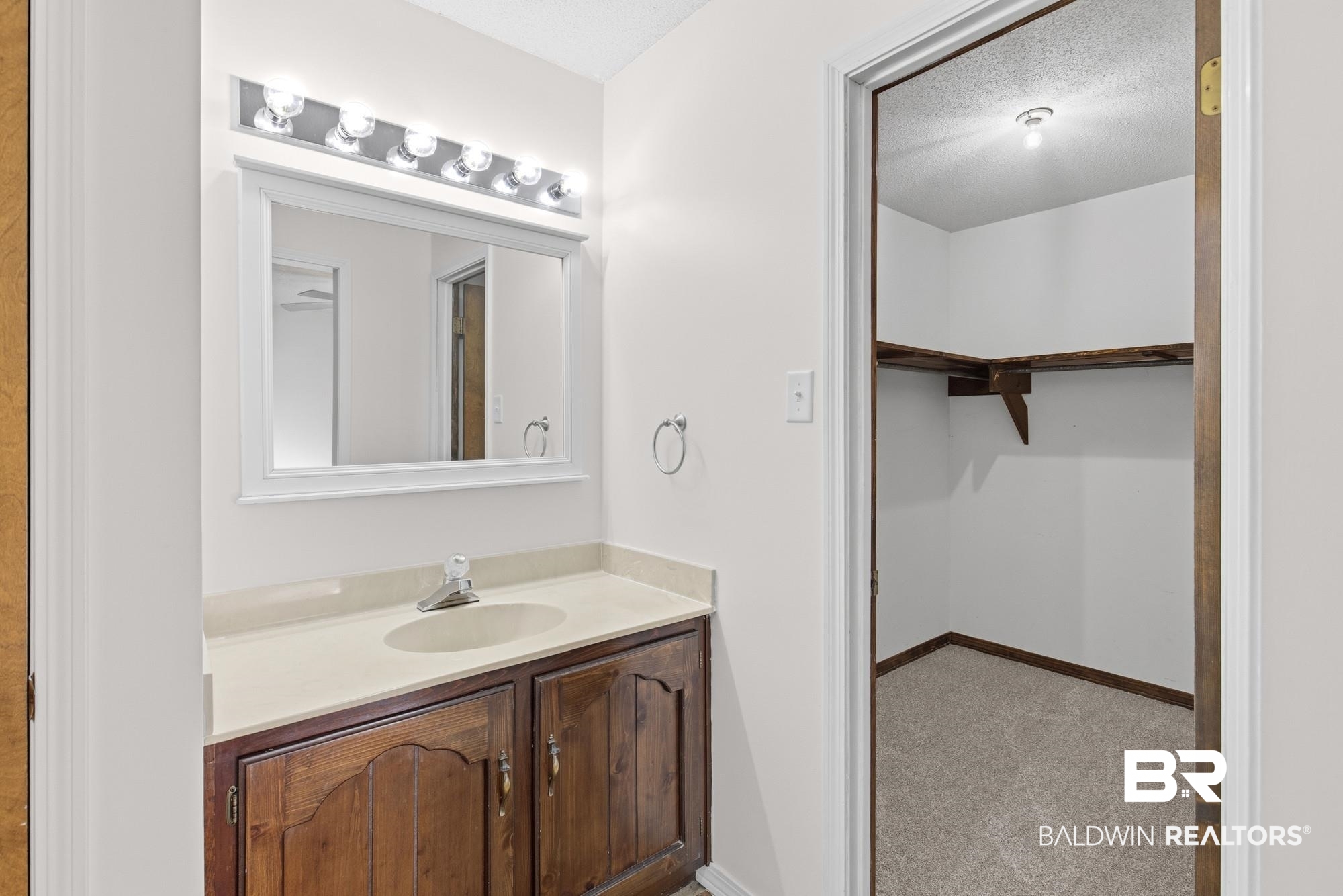 9215 Shiloh Drive Mobile, AL 36695 - Photo 23 of 32 Bathroom with vanity, a spacious closet, light carpet, and a textured ceiling