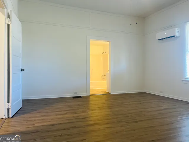 a view of an empty room and wooden floor and a window