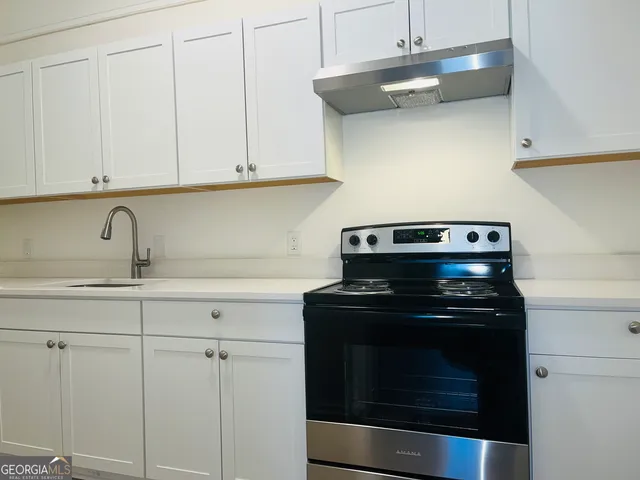 a kitchen with white cabinets and appliances