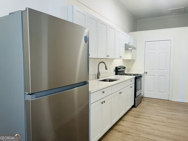 a kitchen with stainless steel appliances a refrigerator and white cabinets