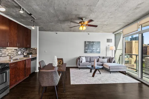 a living room with stainless steel appliances granite countertop furniture and a wooden floor