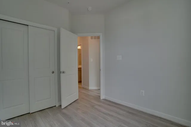 a view of an empty room with closet and wooden floor