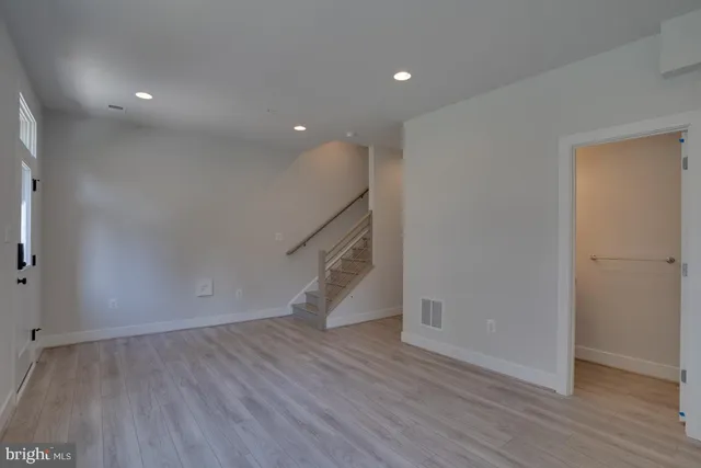 a view of an empty room with wooden floor and closet