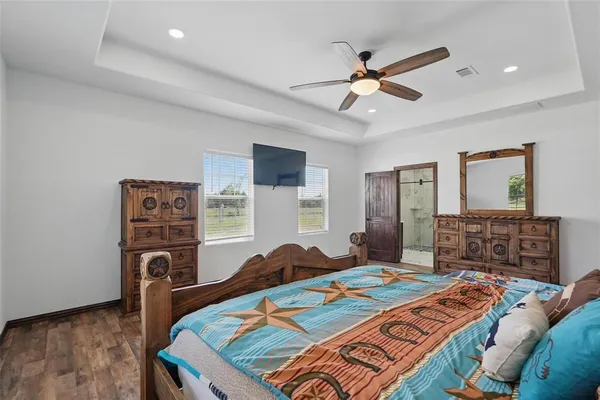 a bedroom with a bed and dresser with wooden floor