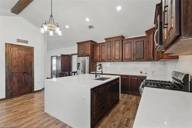 a kitchen with stainless steel appliances granite countertop a sink stove and refrigerator