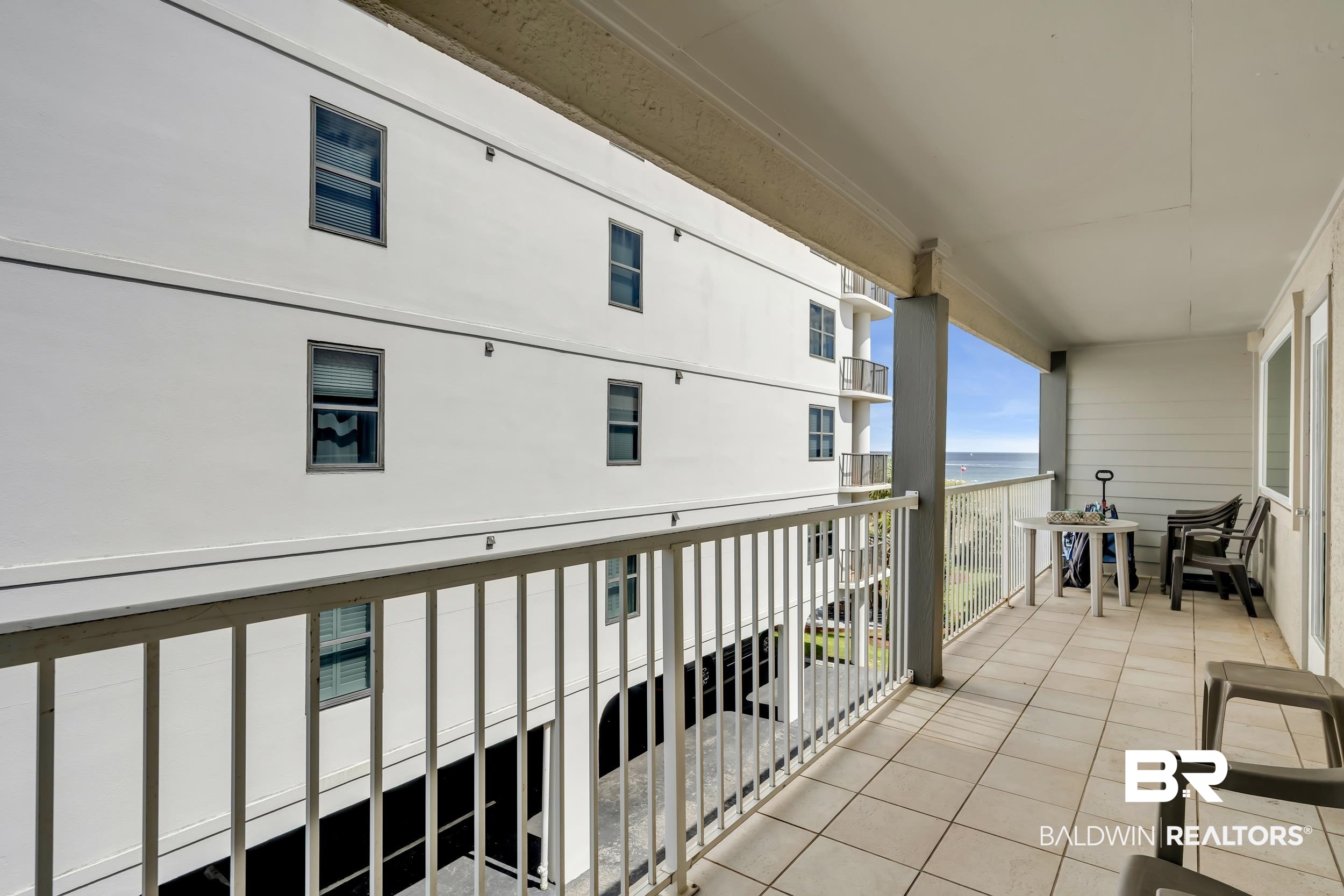 27222 Gulf Road, Unit 33 Orange Beach, AL 36561 - Photo 9 of 29 Expansive covered balcony featuring tile flooring and a metal railing