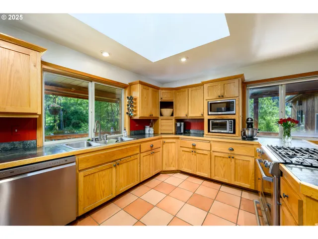 a kitchen with stainless steel appliances granite countertop a stove a sink and a microwave