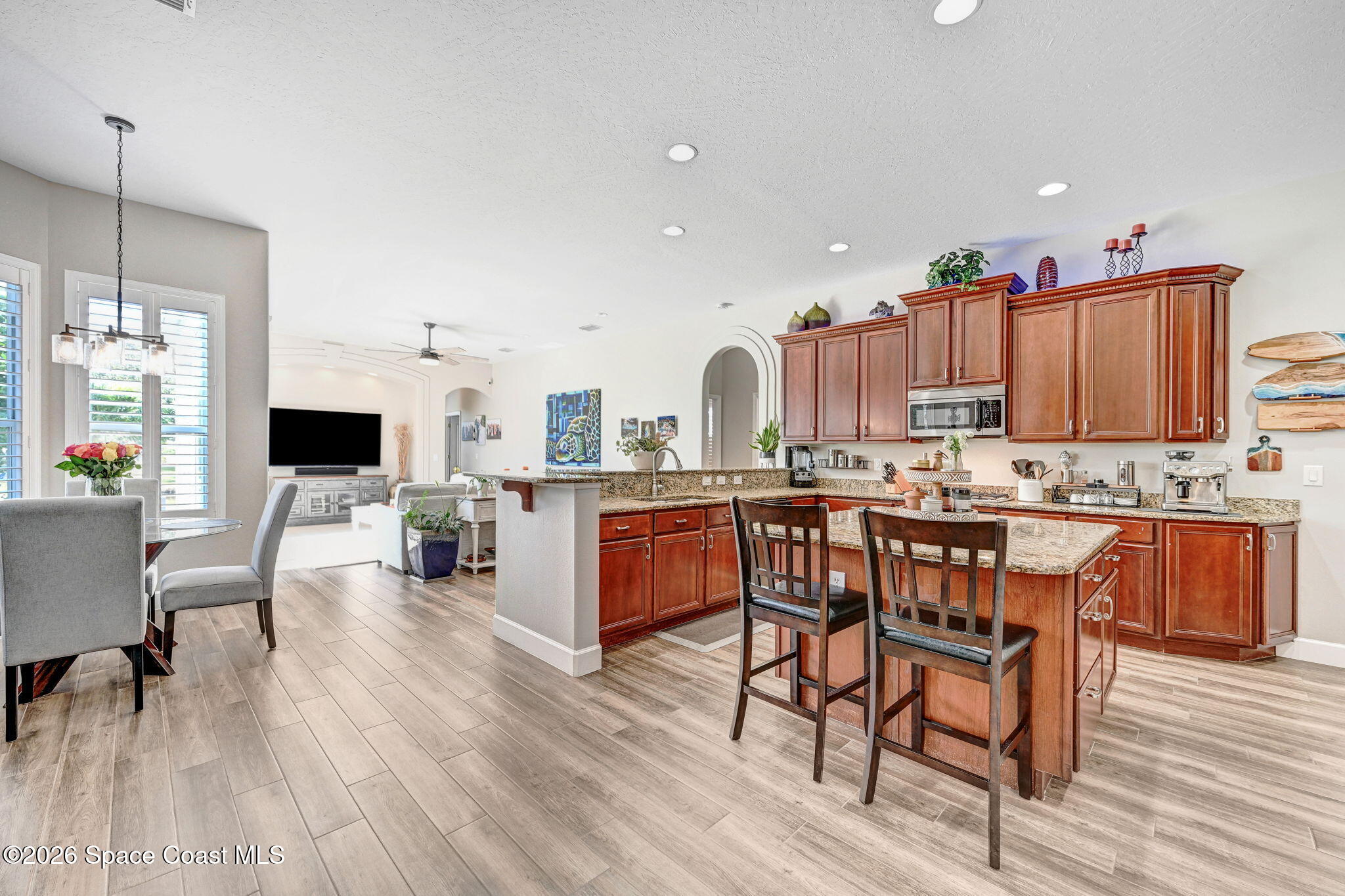 3330 Poseidon Way Indialantic, FL 32903 - Photo 11 of 47 a living room with stainless steel appliances kitchen island granite countertop wooden floor a dining table and chairs