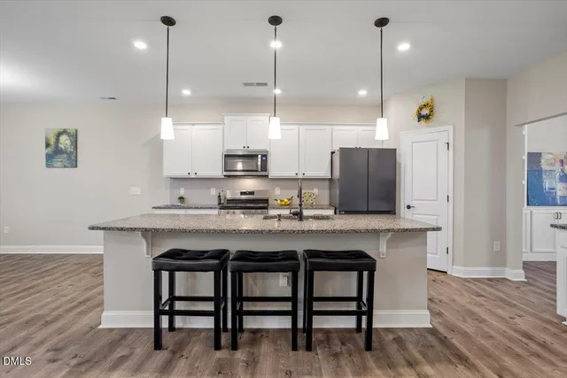 a kitchen with stainless steel appliances granite countertop a sink a refrigerator and a wooden floor