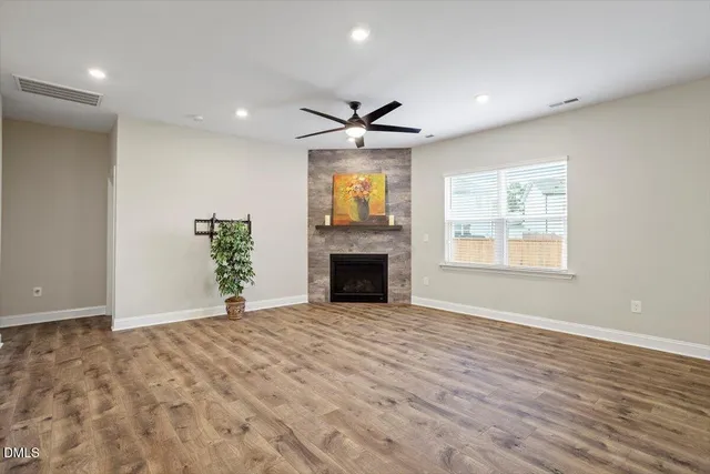 a view of a livingroom with a fireplace a ceiling fan and window