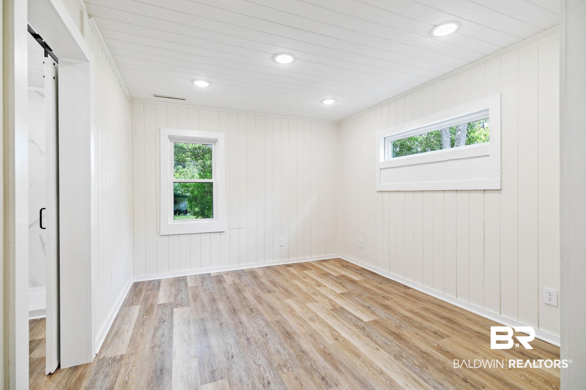 507 Byrne Street Bay Minette, AL 36507 - Photo 16 of 40 Empty room with a barn door and light wood-type flooring