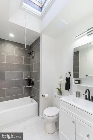 a bathroom with a bathtub shower sink vanity mirror and toilet