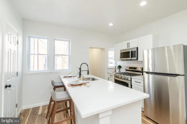 a kitchen with a refrigerator a stove a sink and white cabinets with wooden floor