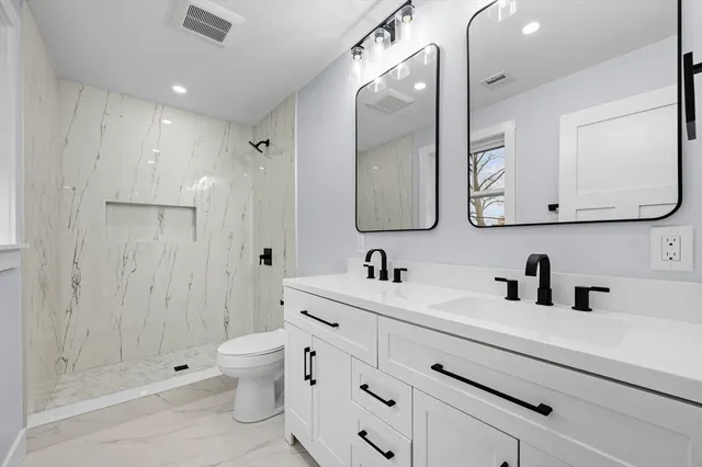 a bathroom with a double vanity sink mirror and toilet