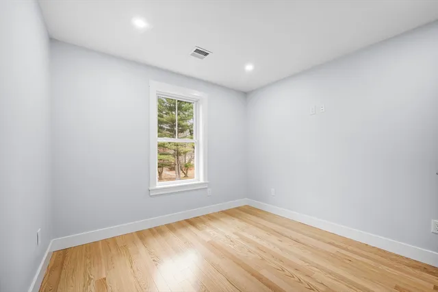 an empty room with wooden floor and window