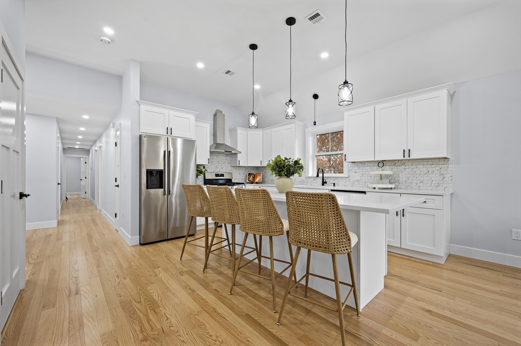 69 Readville Street, Unit B Boston, MA 02136 - Photo 7 of 38 a kitchen with stainless steel appliances granite countertop a refrigerator a sink dishwasher a stove and white cabinets with wooden floor