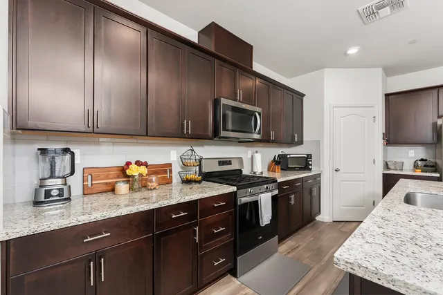 a kitchen with granite countertop stainless steel appliances a sink a stove and cabinets