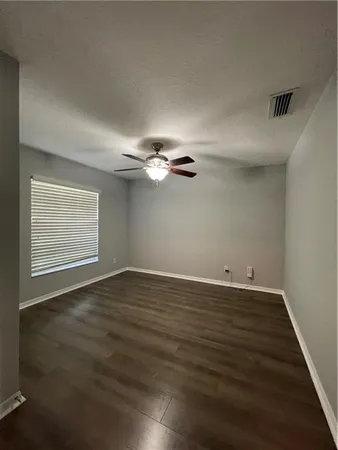 an empty room with wooden floor fan and windows